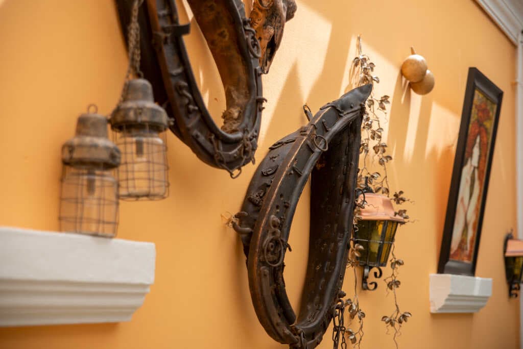 Alte Kummete und Laternen an der Wand des Gastraums