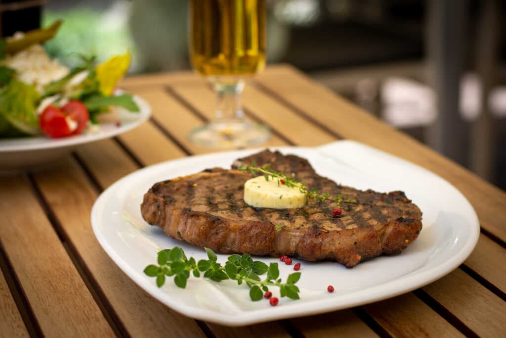 Steak mit Kräuterbutter auf dem Gartentisch